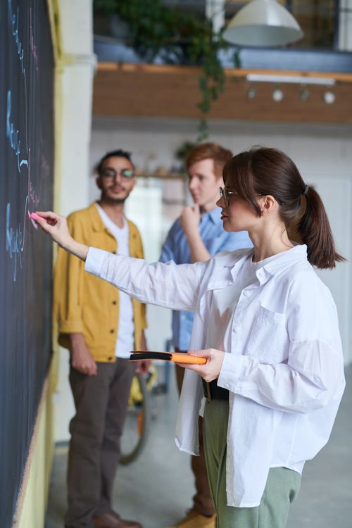 Femme présentant à ses collègues attentifs en arrière-plan.
