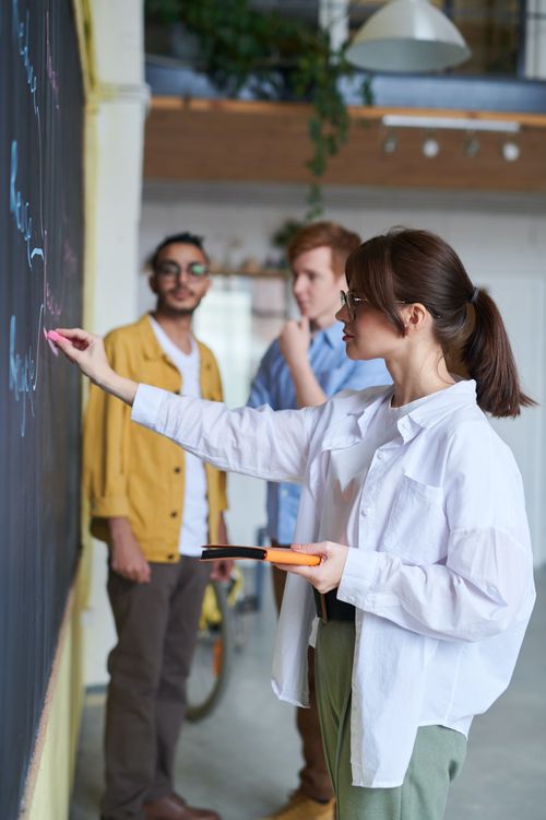 Femme présentant à ses collègues attentifs en arrière-plan.