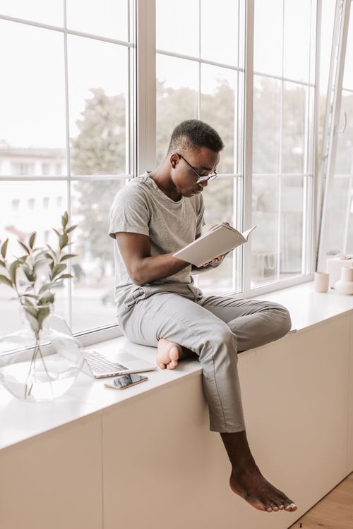 Homme lisant tranquillement près de la fenêtre.